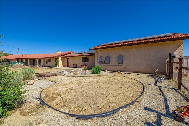 14320 Kiptree Dr, Lake Hughes, CA 93532 - rear view of house featuring stucco siding, roof mounted solar panels, and a fenced backyard