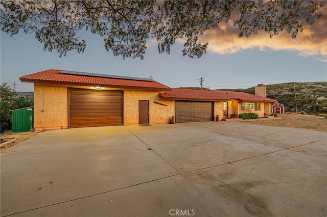 14320 Kiptree Dr, Lake Hughes, CA 93532 - view of front of house featuring a tiled roof, an attached garage, driveway, roof mounted solar panels, and stucco siding