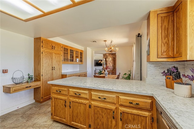 14320 Kiptree Dr, Lake Hughes, CA 93532 - kitchen featuring a peninsula, tasteful backsplash, brown cabinets, a chandelier, and stainless steel dishwasher
