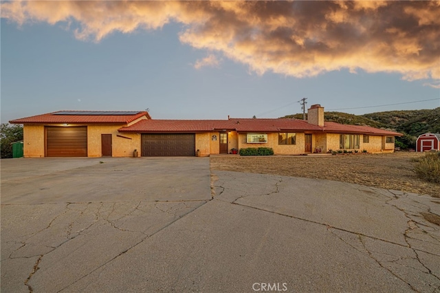 14320 Kiptree Dr, Lake Hughes, CA 93532 - view of front facade with an attached garage, concrete driveway, roof mounted solar panels, a chimney, and a tile roof