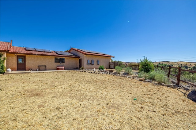14320 Kiptree Dr, Lake Hughes, CA 93532 - rear view of property with solar panels, a fenced backyard, a tiled roof, and stucco siding