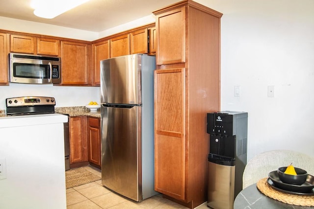 12191 Cuyamaca College Dr E Unit 703, San Diego, CA 92019 - kitchen featuring appliances with stainless steel finishes, brown cabinetry, light tile patterned flooring, and light stone counters