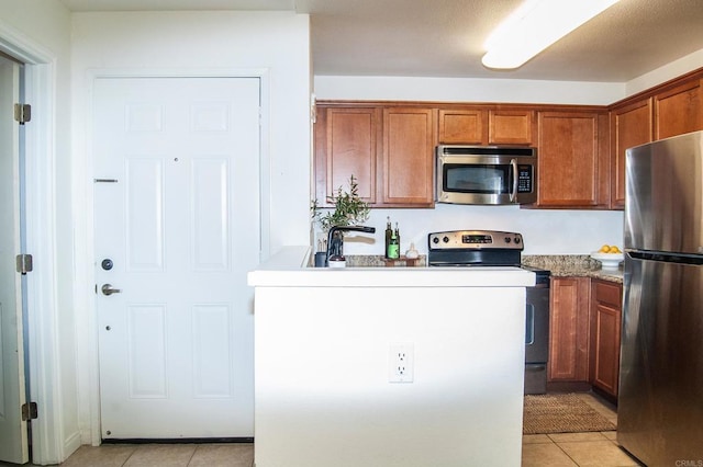 12191 Cuyamaca College Dr E Unit 703, San Diego, CA 92019 - kitchen featuring appliances with stainless steel finishes, light tile patterned floors, and brown cabinetry
