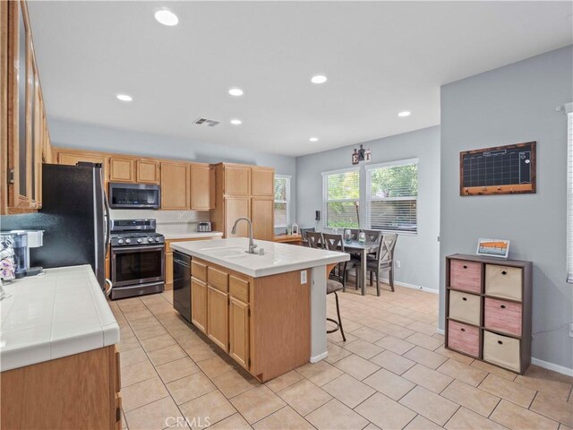 28323 Roman Ct, Saugus, CA 91350 - kitchen with appliances with stainless steel finishes, tile countertops, an island with sink, recessed lighting, and a breakfast bar