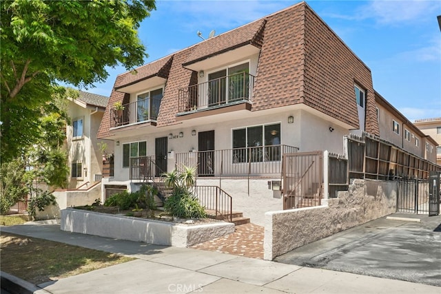 429 E Providencia Ave Unit B, Burbank, CA 91501 - view of front facade with a shingled roof, mansard roof, stucco siding, a gate, and a balcony