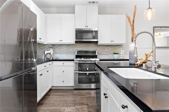 28 Sembrio St, Rancho Mission Viejo, CA 92694 - kitchen featuring appliances with stainless steel finishes, dark wood finished floors, tasteful backsplash, white cabinetry, and decorative light fixtures