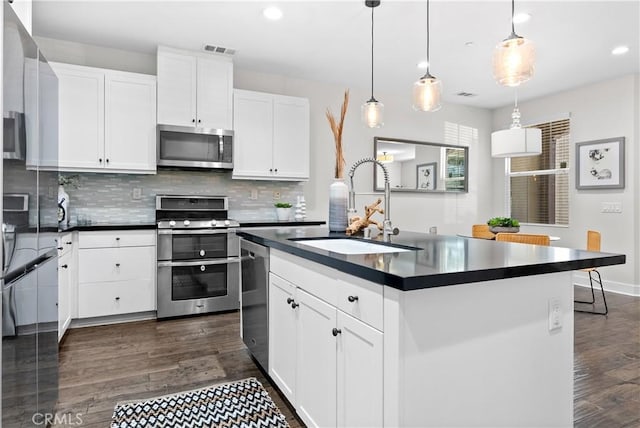 28 Sembrio St, Rancho Mission Viejo, CA 92694 - kitchen with appliances with stainless steel finishes, dark countertops, decorative backsplash, dark wood-type flooring, and recessed lighting