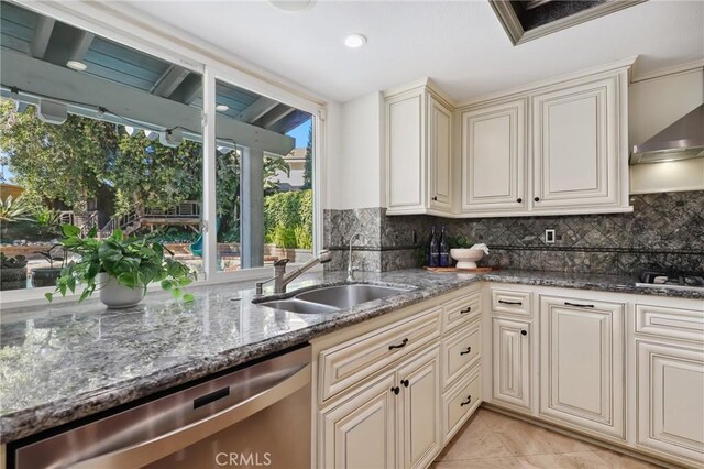 24622 Cresta Ct, Laguna Hills, CA 92653 - kitchen with stainless steel appliances, backsplash, dark stone counters, cream cabinetry, and wall chimney exhaust hood