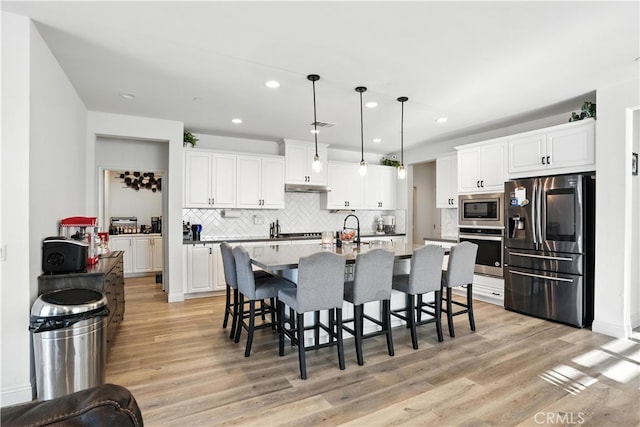 11715 Periwinkle Pl, Jurupa Valley, CA 91752 - kitchen featuring appliances with stainless steel finishes, a kitchen bar, backsplash, white cabinetry, and recessed lighting