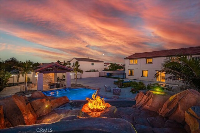 11715 Periwinkle Pl, Jurupa Valley, CA 91752 - pool at dusk with an outdoor fire pit, a gazebo, a fenced backyard, and a patio