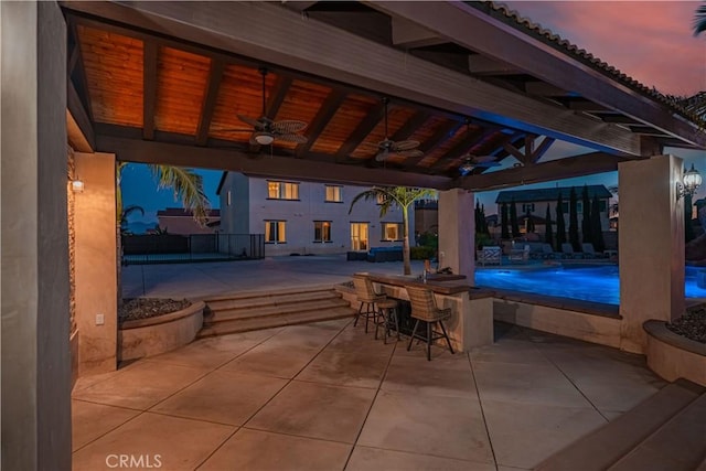 11715 Periwinkle Pl, Jurupa Valley, CA 91752 - patio terrace at dusk with a ceiling fan, a patio area, and a pool