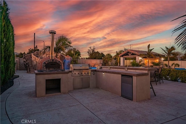 11715 Periwinkle Pl, Jurupa Valley, CA 91752 - patio terrace at dusk featuring an outdoor kitchen, a bar, and a patio area