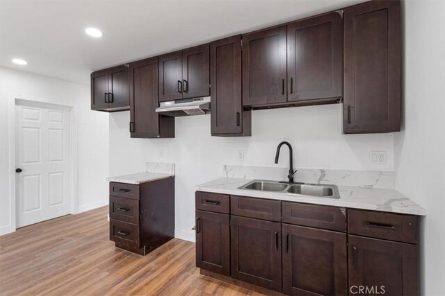 727 E 94th St, Los Angeles, CA 90002 - kitchen with under cabinet range hood, dark brown cabinets, light wood-style flooring, recessed lighting, and light stone countertops