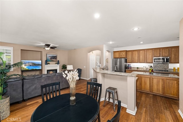 13014 Bermuda Ave, Chino, CA 91710 - dining area with a ceiling fan, arched walkways, dark wood finished floors, a warm lit fireplace, and recessed lighting