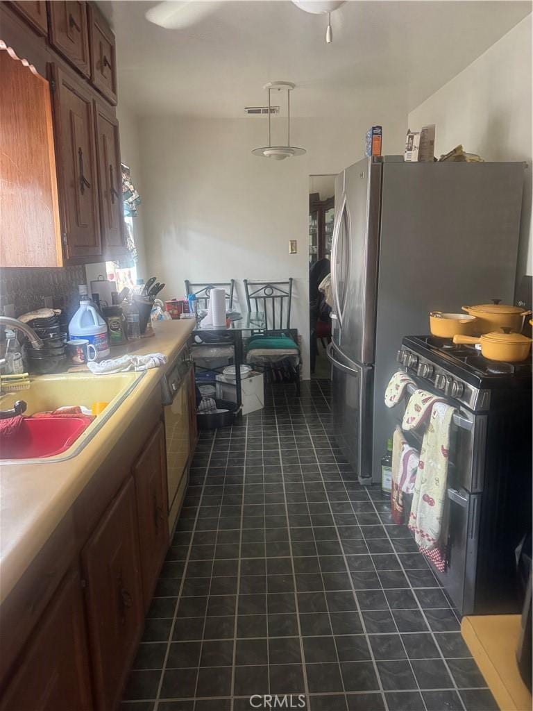 3500 S Norton Ave, Los Angeles, CA 90018 - kitchen with light countertops, freestanding refrigerator, dark tile patterned floors, and backsplash