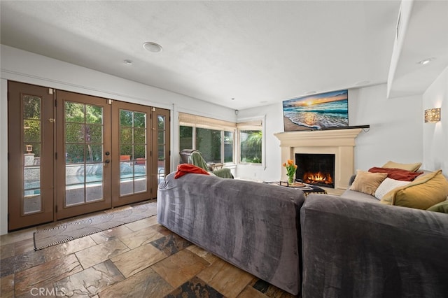 27681 Paseo Esteban, San Juan Capistrano, CA 92675 - living room with french doors, a warm lit fireplace, stone tile floors, plenty of natural light, and recessed lighting