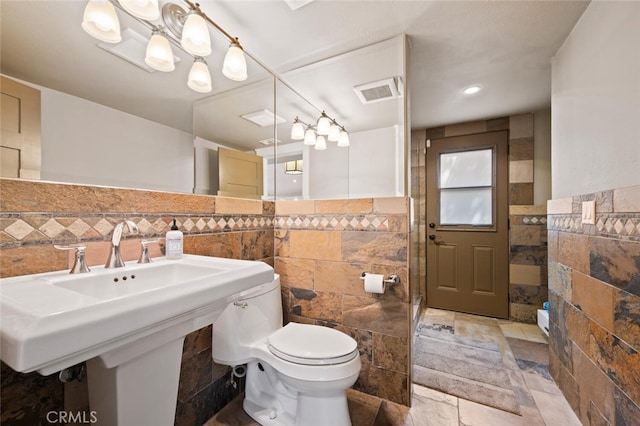 27681 Paseo Esteban, San Juan Capistrano, CA 92675 - bathroom featuring tile walls, a chandelier, stone tile flooring, a shower with door, and wainscoting