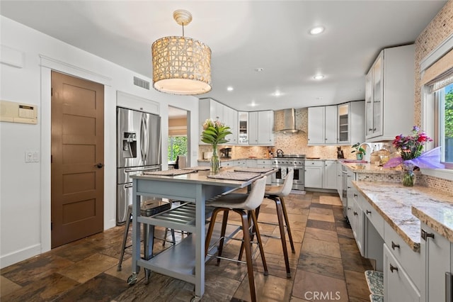 27681 Paseo Esteban, San Juan Capistrano, CA 92675 - kitchen with appliances with stainless steel finishes, wall chimney exhaust hood, decorative backsplash, light stone counters, and glass insert cabinets