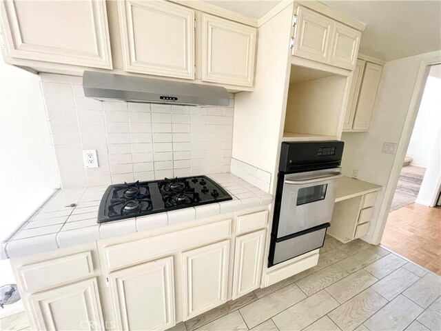 640 S Lake Ave Unit 306, Pasadena, CA 91106 - kitchen with tile counters, stainless steel oven, black gas cooktop, exhaust hood, and backsplash