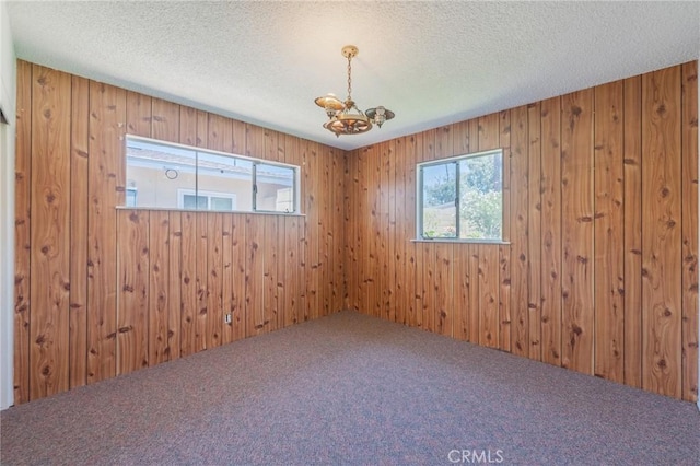 2001 W Jan Way, Santa Ana, CA 92704 - carpeted empty room featuring a chandelier, plenty of natural light, wooden walls, and a textured ceiling