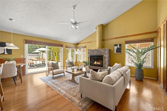 26017 Redbluff Dr, Calabasas, CA 91302 - living room featuring a textured ceiling, a ceiling fan, a brick fireplace, light wood-style floors, and high vaulted ceiling
