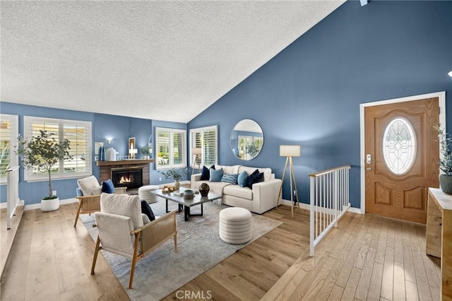 26017 Redbluff Dr, Calabasas, CA 91302 - living area featuring hardwood / wood-style flooring, a textured ceiling, high vaulted ceiling, a fireplace, and healthy amount of natural light