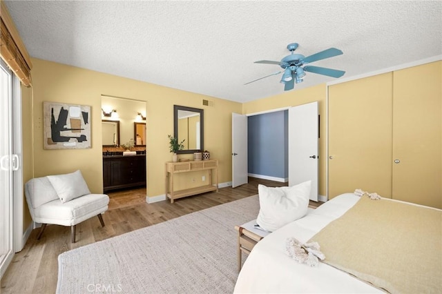 26017 Redbluff Dr, Calabasas, CA 91302 - bedroom with light wood-type flooring, a textured ceiling, multiple closets, connected bathroom, and a ceiling fan