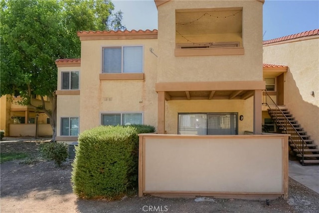 1130 W Blaine St, Riverside, CA 92507 - rear view of house with stairway, a tile roof, and stucco siding