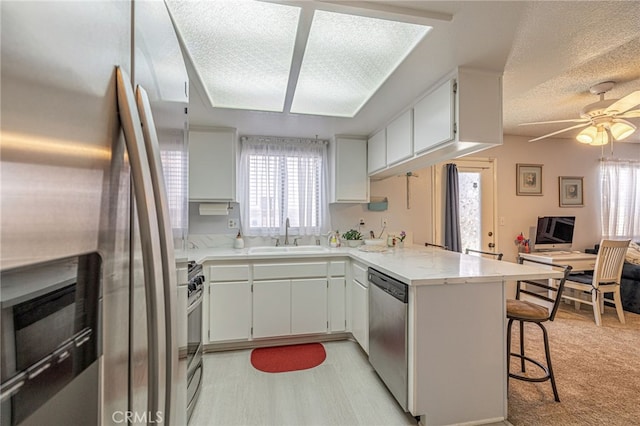 43840 Bobby Jones Dr Unit 22, Lancaster, CA 93536 - kitchen with stainless steel appliances, a peninsula, a ceiling fan, a kitchen breakfast bar, and a textured ceiling