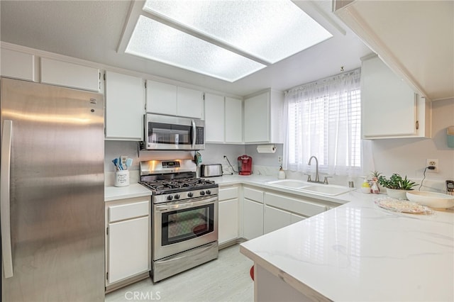 43840 Bobby Jones Dr Unit 22, Lancaster, CA 93536 - kitchen featuring appliances with stainless steel finishes, white cabinetry, light wood-type flooring, and light stone countertops