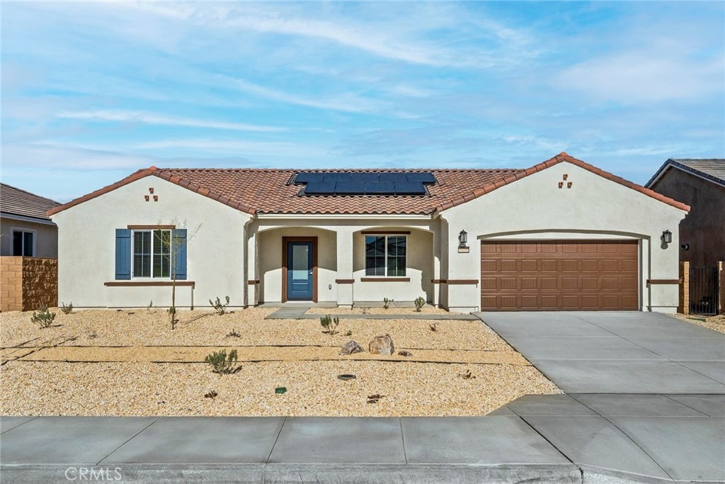 14811 Indigo Rd, Apple Valley, CA 92307 - mediterranean / spanish home with a tiled roof, an attached garage, roof mounted solar panels, stucco siding, and concrete driveway