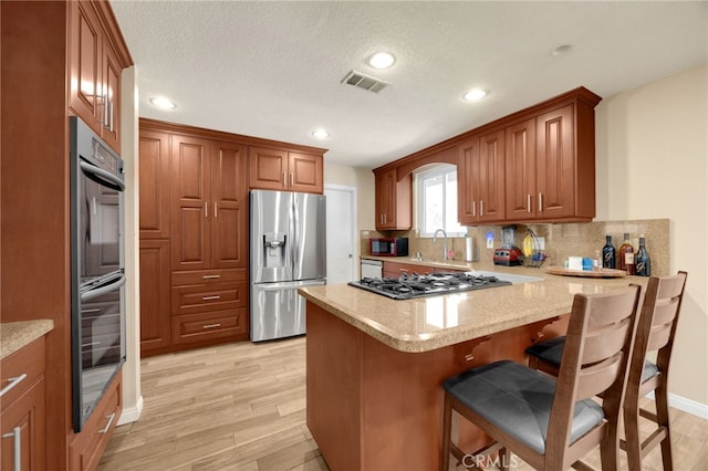 1219 N Van Buren St, Placentia, CA 92870 - kitchen with stainless steel appliances, a peninsula, light wood-type flooring, tasteful backsplash, and recessed lighting
