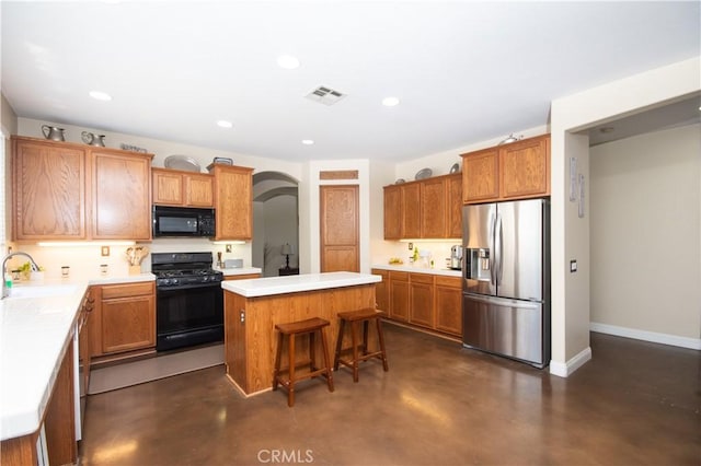 8718 Snowmass Peak Way, Riverside, CA 92508 - kitchen featuring black appliances, finished concrete floors, a kitchen island, arched walkways, and recessed lighting