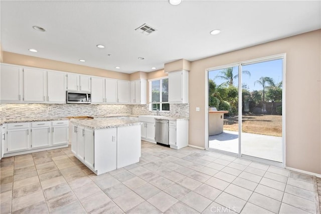 15353 Isabel Ln, Fontana, CA 92336 - kitchen featuring stainless steel appliances, tasteful backsplash, a kitchen island, white cabinets, and light stone counters