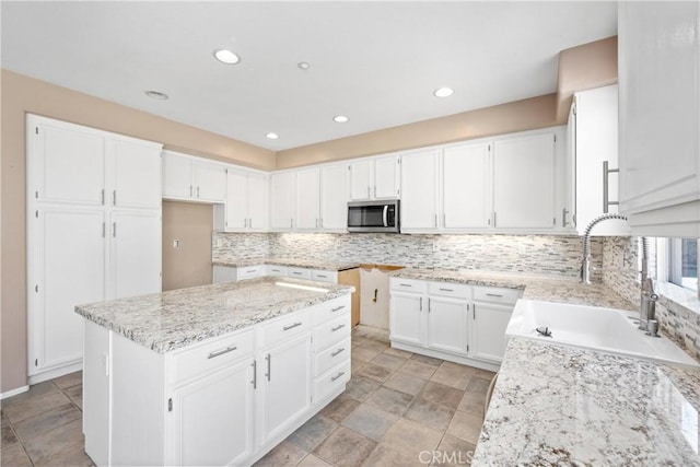 15353 Isabel Ln, Fontana, CA 92336 - kitchen featuring stainless steel microwave, light stone countertops, tasteful backsplash, white cabinetry, and recessed lighting