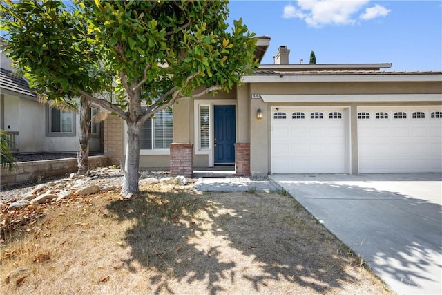 15353 Isabel Ln, Fontana, CA 92336 - view of front of house with concrete driveway, a garage, stucco siding, and brick siding