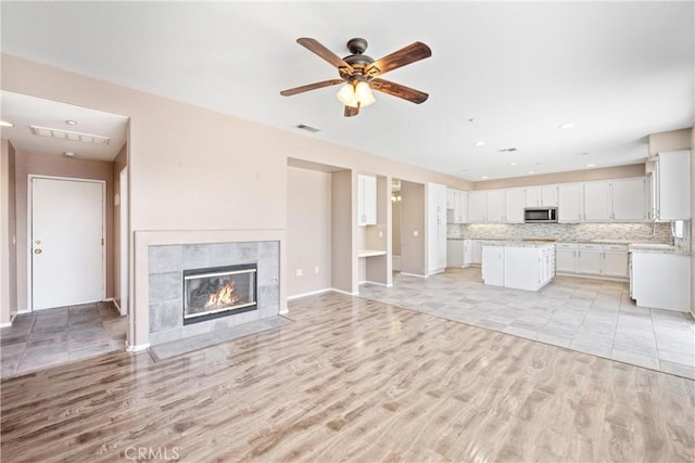 15353 Isabel Ln, Fontana, CA 92336 - unfurnished living room featuring light wood-type flooring, a ceiling fan, a tiled fireplace, and recessed lighting
