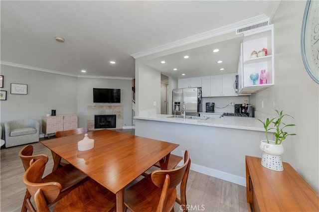 2323 S Cutty Way Unit 58, Anaheim, CA 92802 - dining room featuring recessed lighting, a fireplace, light wood-style flooring, and ornamental molding