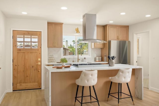 4936 Mount Elbrus Dr, San Diego, CA 92117 - kitchen with appliances with stainless steel finishes, island exhaust hood, light wood-style flooring, light countertops, and a center island