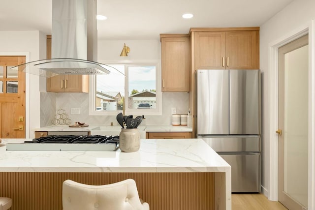 4936 Mount Elbrus Dr, San Diego, CA 92117 - kitchen with freestanding refrigerator, island exhaust hood, light stone countertops, tasteful backsplash, and light brown cabinets