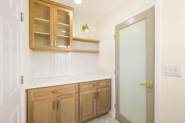 4936 Mount Elbrus Dr, San Diego, CA 92117 - kitchen featuring tasteful backsplash, glass insert cabinets, light stone counters, open shelves, and brown cabinetry