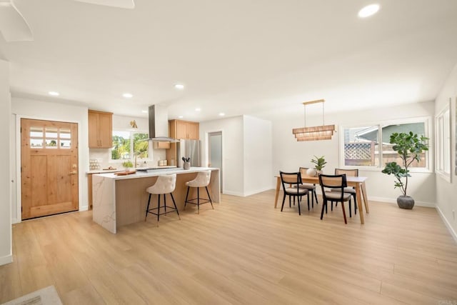 4936 Mount Elbrus Dr, San Diego, CA 92117 - kitchen with island range hood, light wood-style flooring, a kitchen island, a kitchen breakfast bar, and recessed lighting