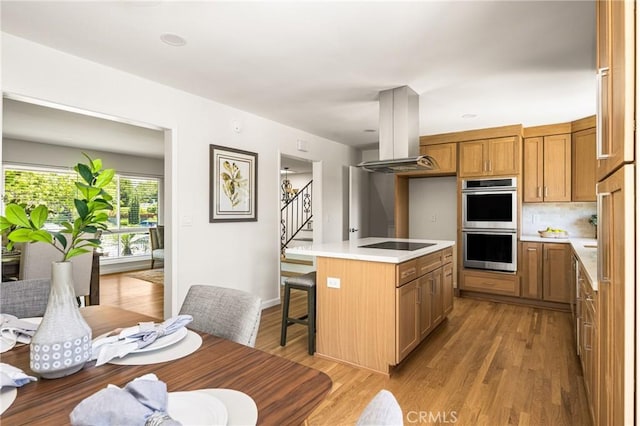 17542 Rainier Dr, North Tustin, CA 92705 - kitchen featuring island exhaust hood, stainless steel double oven, black electric cooktop, and light countertops