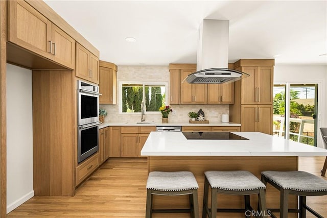 17542 Rainier Dr, North Tustin, CA 92705 - kitchen with island exhaust hood, stainless steel appliances, a kitchen bar, tasteful backsplash, and recessed lighting