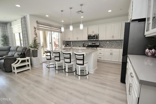 1622 Trailview Dr, Beaumont, CA 92223 - kitchen with stainless steel appliances, open floor plan, a breakfast bar, white cabinetry, and decorative backsplash