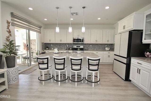 1622 Trailview Dr, Beaumont, CA 92223 - kitchen featuring appliances with stainless steel finishes, white cabinets, a kitchen breakfast bar, tasteful backsplash, and glass insert cabinets