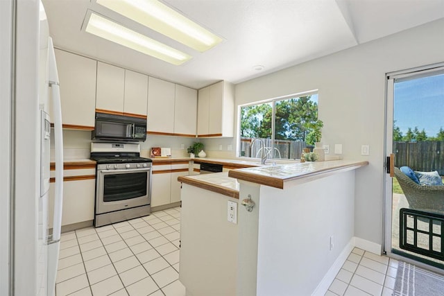 5452 Gooseberry Way, Oceanside, CA 92057 - kitchen with stainless steel gas range oven, black microwave, a peninsula, white refrigerator with ice dispenser, and light tile patterned flooring