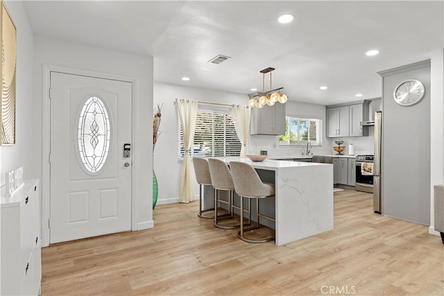 6002 Calvin Cir, Huntington Beach, CA 92647 - kitchen with gray cabinets, stainless steel stove, a kitchen bar, light countertops, and light wood-type flooring