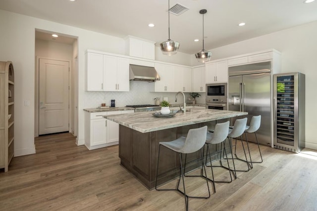 744 Adelaide Cir, Encinitas, CA 92024 - kitchen with built in appliances, beverage cooler, wall chimney exhaust hood, white cabinets, and light wood finished floors