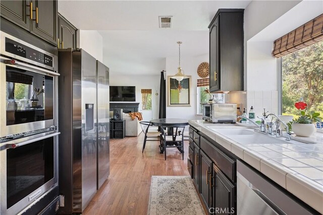 8042 Masefield Ct, West Hills, CA 91304 - kitchen with appliances with stainless steel finishes, tile countertops, light wood-type flooring, and plenty of natural light